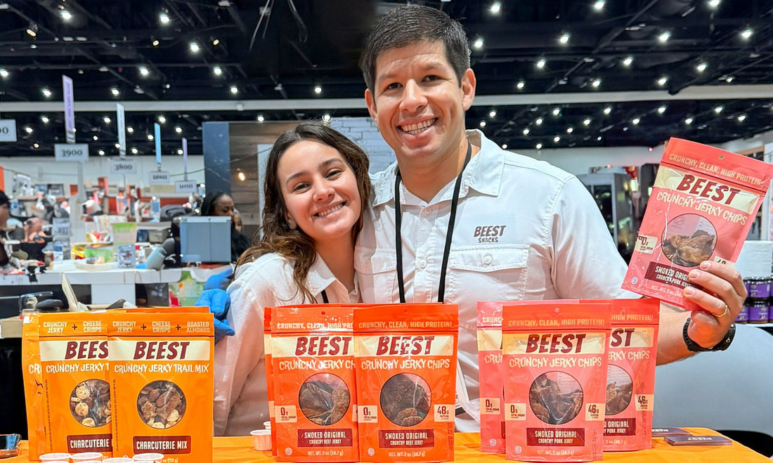 BEEST Snacks co-founder Lucas Prado at a booth displaying Crunchy Beef Jerky Chips, Crunchy Pork Jerky Chips, and Charcuterie Trail Mix.