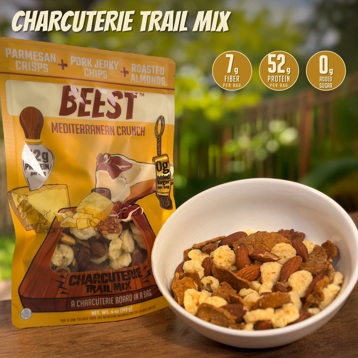 BEEST Charcuterie Trail Mix bag beside a bowl of pork jerky chips, parmesan crisps and roasted almonds: 52g protein, 0g Added Sugar and 7g fiber per bag