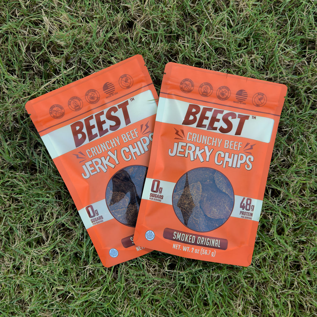 Two bags of BEEST Beef Jerky Chips, Smoked Original, fanned out on green grass