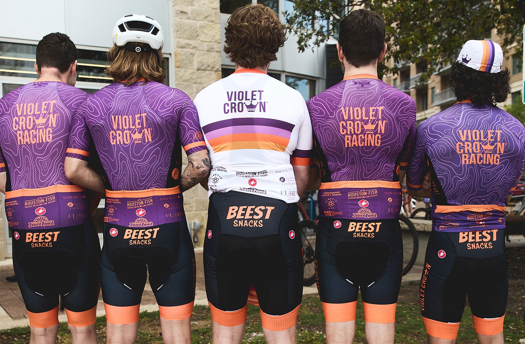 Five cyclists wearing Violet Crown Racing and Beast Snacks cycling gear outdoors.