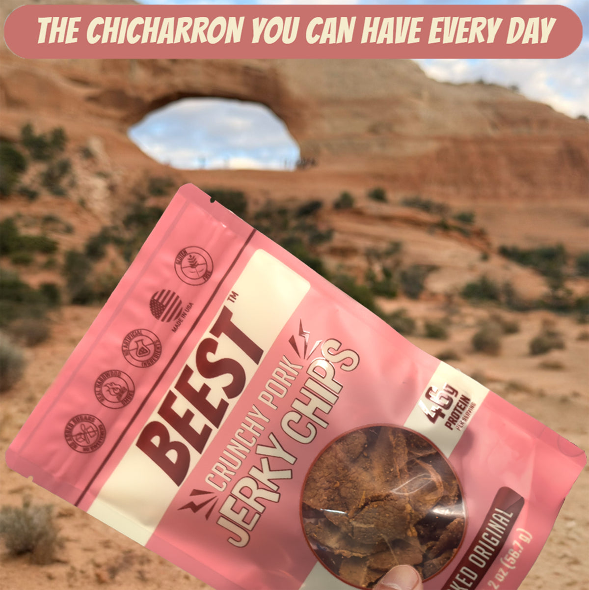 A hand holding a bag of BEEST Pork Jerky Chips in a desert canyon: the chicharrón you can have every day
