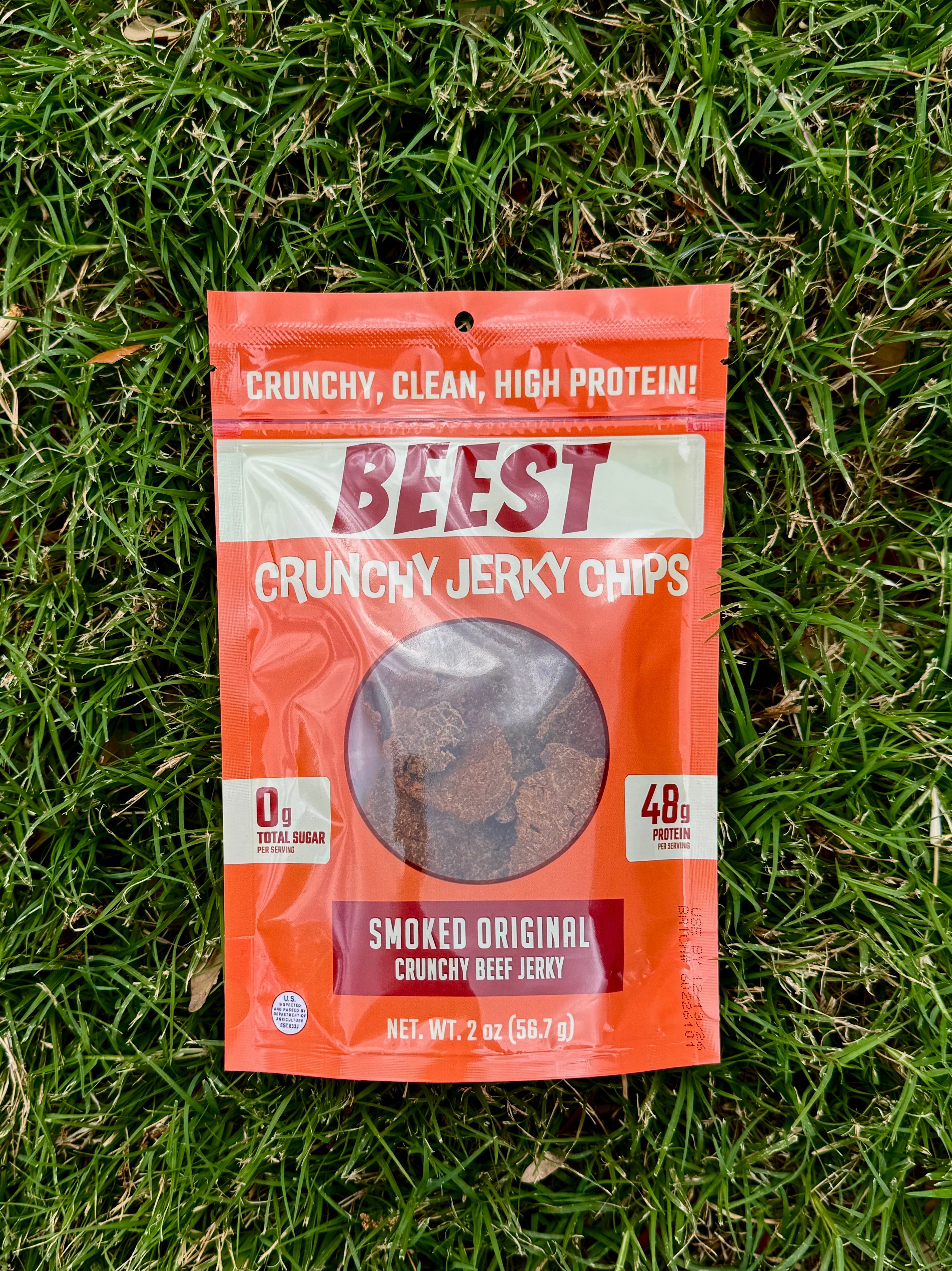 BEEST Crunchy Beef Jerky Chips Smoked Original package on grass, high-protein snack with 48g protein and 0g total sugar
