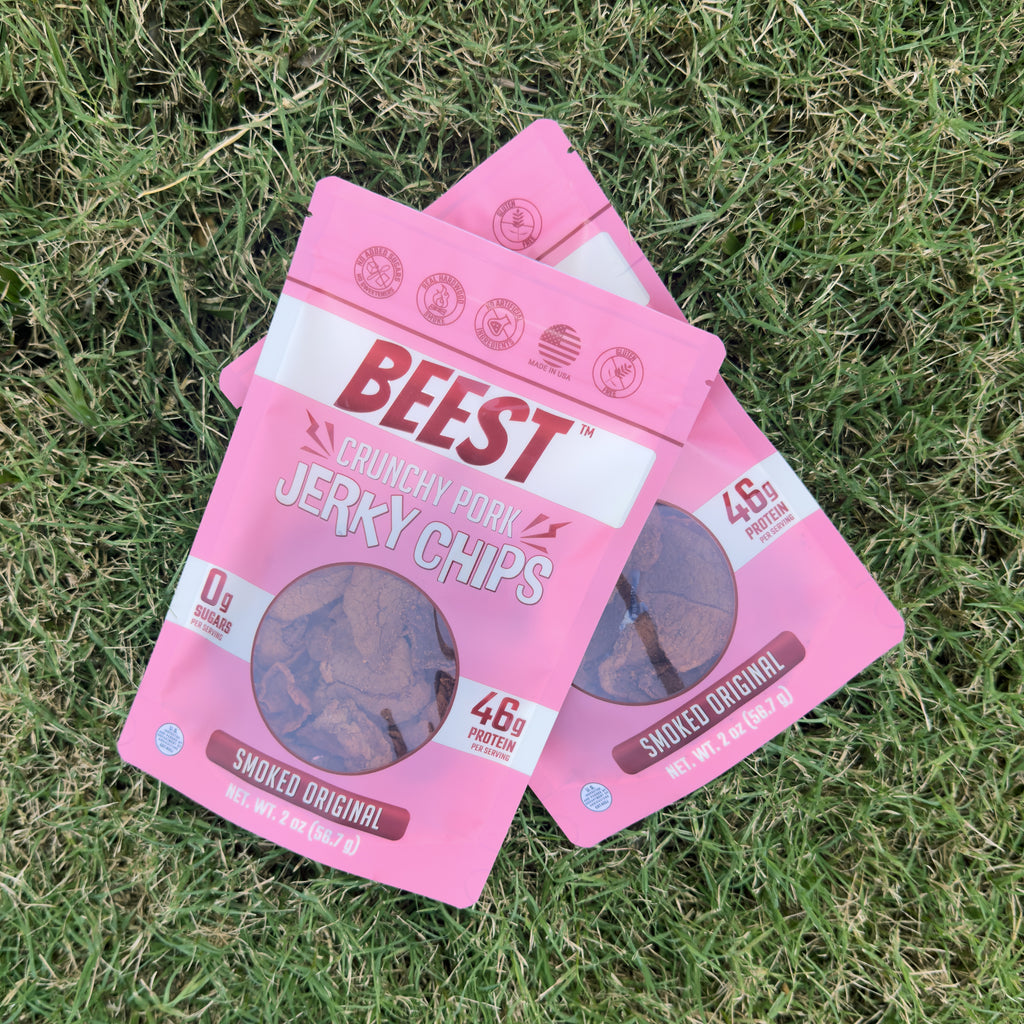 Two bags of BEEST Pork Jerky Chips, Smoked Original, crossed on green grass