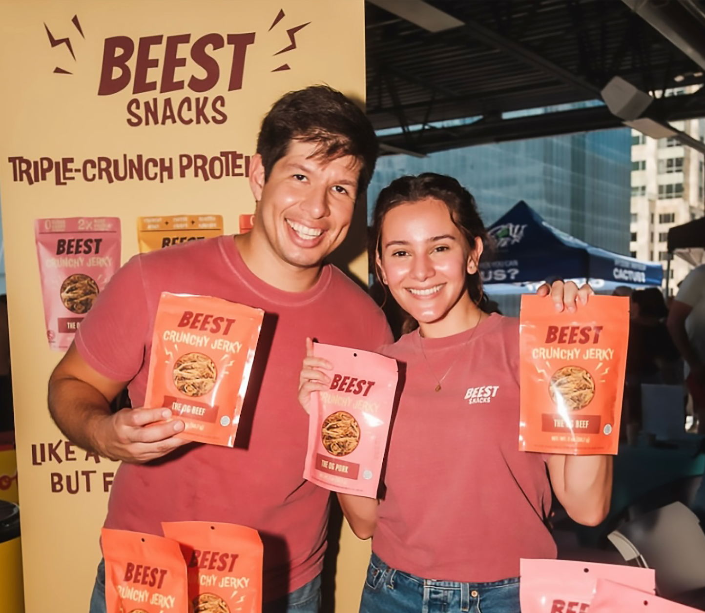 Founder holding BEEST snacks products in front of a BEEST Snacks display.