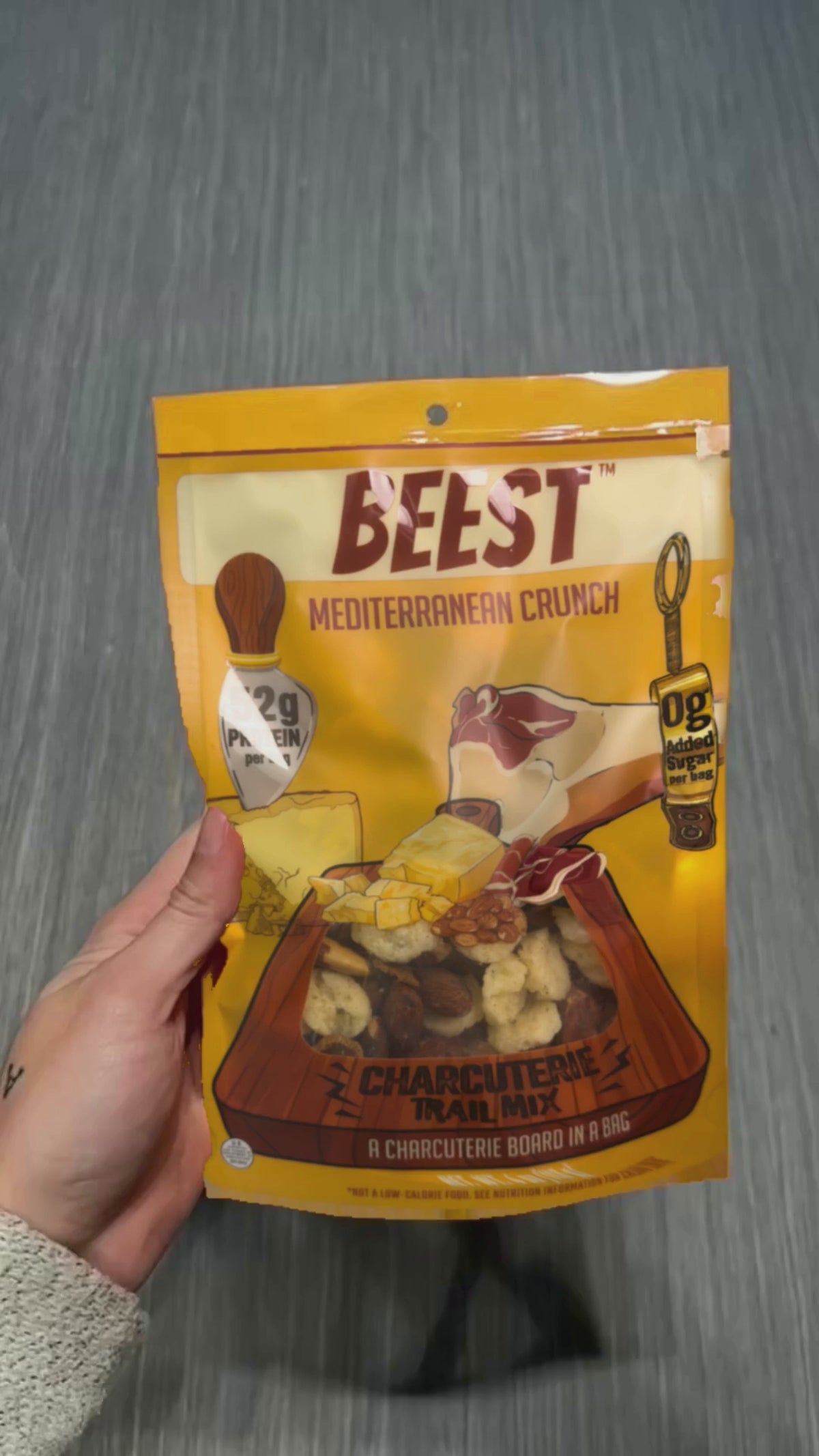 A VIDEO OF A CHARCUTERIE TRAIL MIX BEING OPENED AND SHOWING THE CONTENTS THEN A WOMAN EATING ONE INGREDIENT AT A TIME.